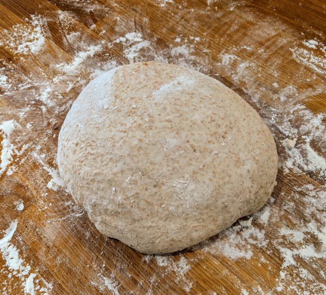 Ball of fermented dough resting on floured worktop