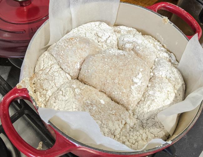 Scored dough on parchment paper in Dutch Oven ready to bake