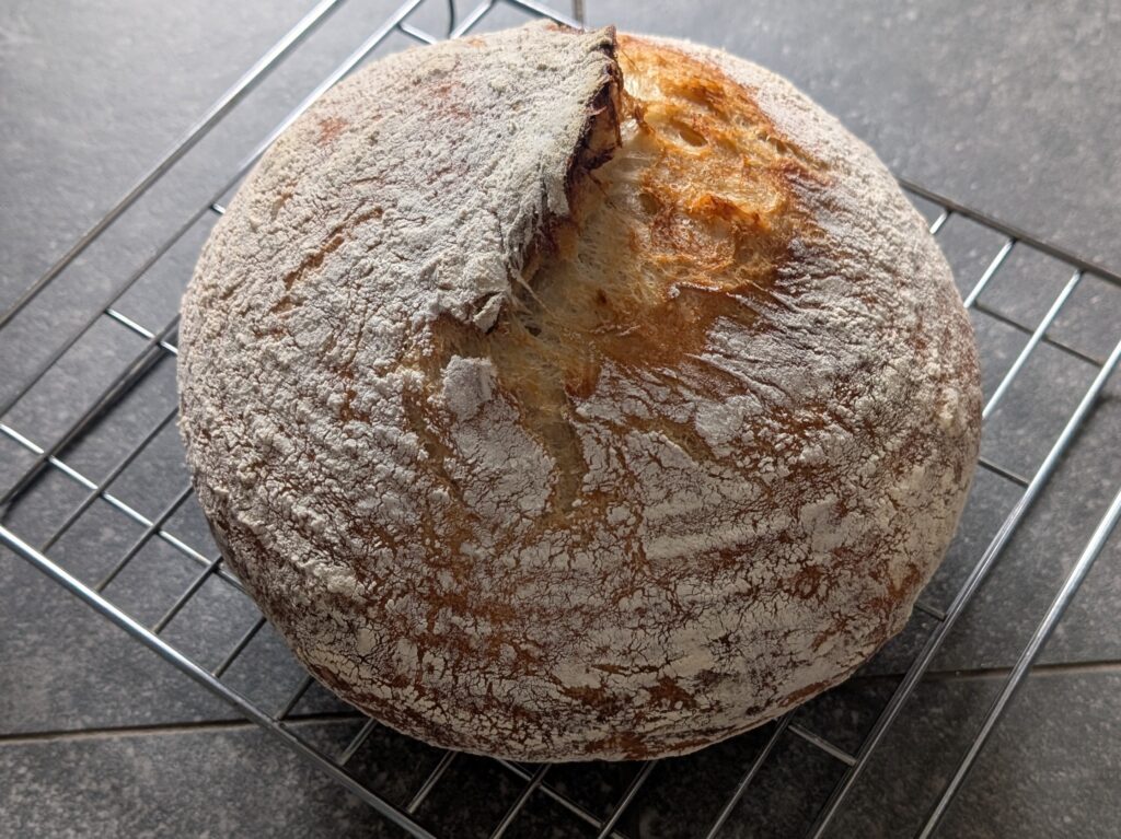 A round sourdough loaf on a wire rack